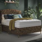 Leopard print headboard and divan base in a green bedroom with plants