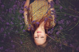 Woman meditating in a field of purple flowers